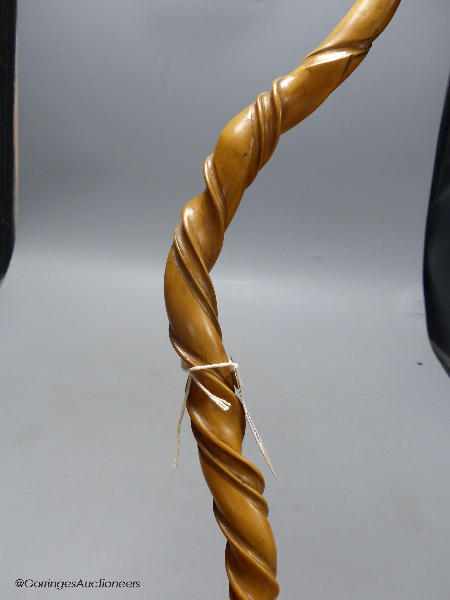 A carved wood walking stick in the style of a narwal tusk